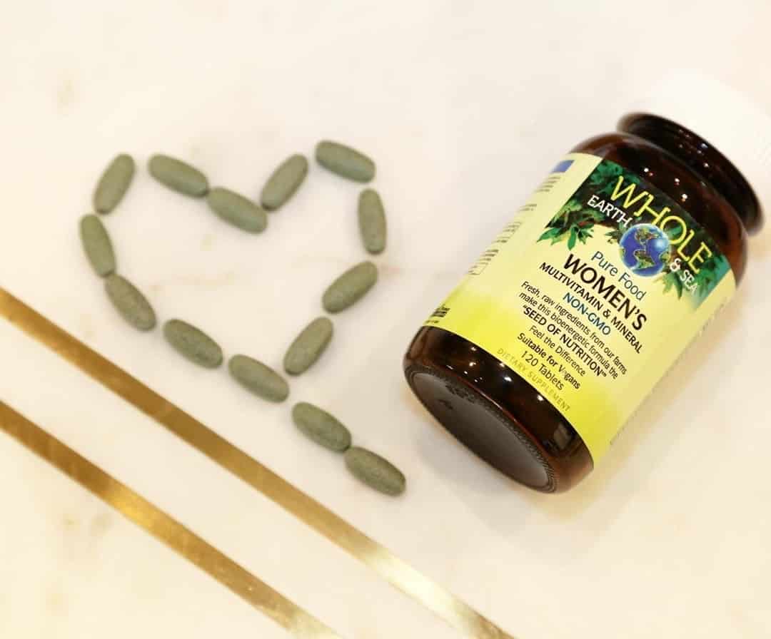 looking down on a desk with a bottle of whole earth and sea women's multivitamins laying down. beside it are 14 multi tablets laid out in a heart shape