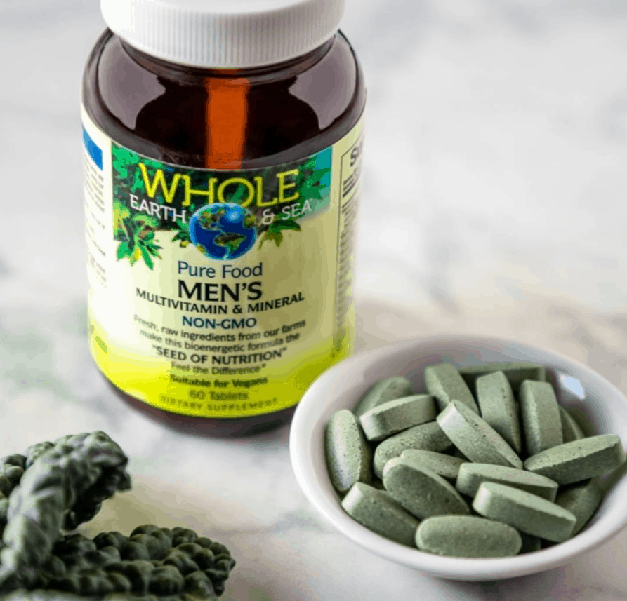 bottle of Whole Earth & Sea Men's Multivitamin and Mineral bottle set in front of a small bowl of the tablets poured into it and a bit of kale off to the side