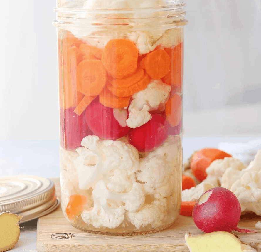 mason jar layered with veggies in it. Carrots, cauliflower, and radishes 